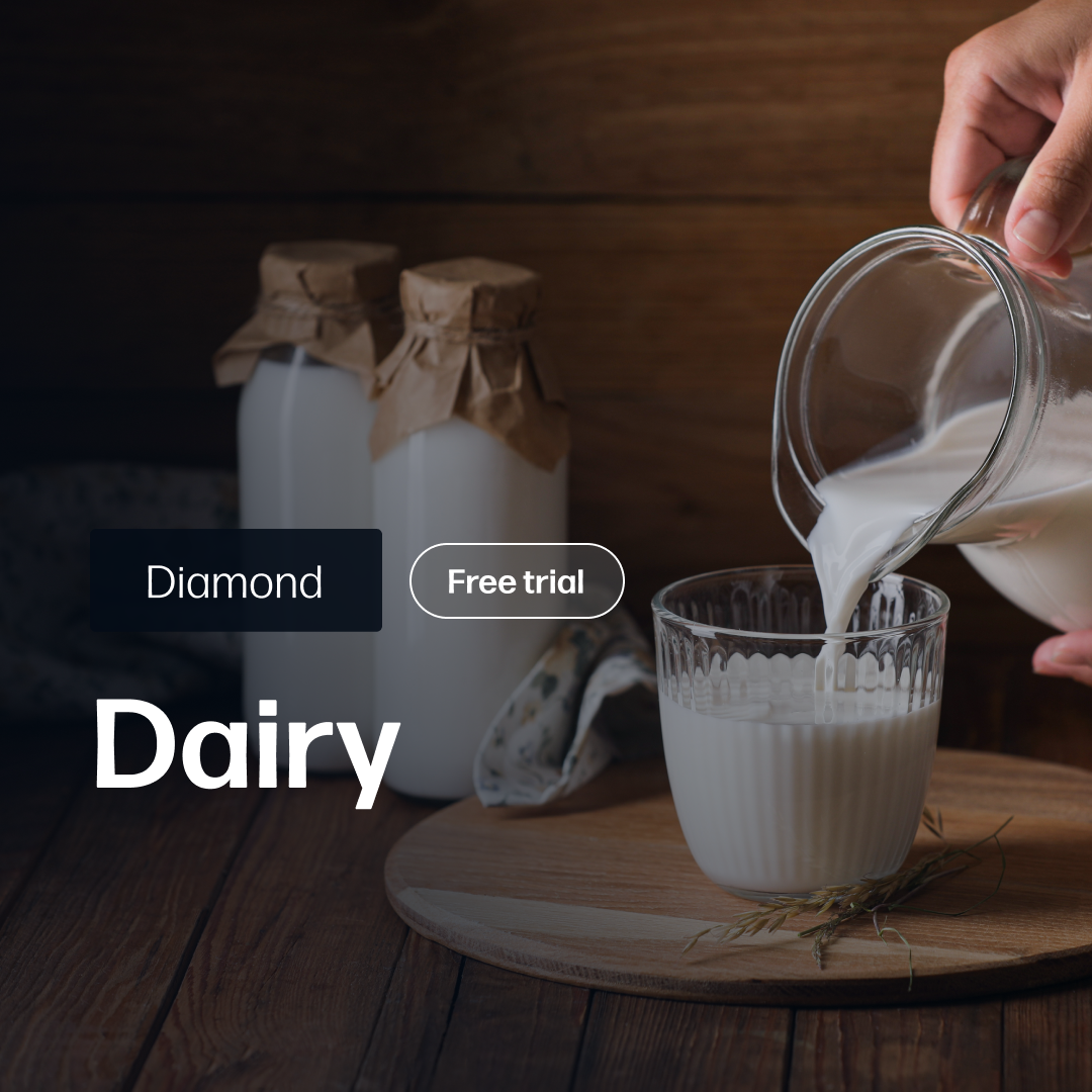 Hand pouring fresh milk from a clear glass jug into a textured glass on a wooden surface with two bottles wrapped in brown paper in the background, representing Dairy Market Reports Subscription | Diamond.