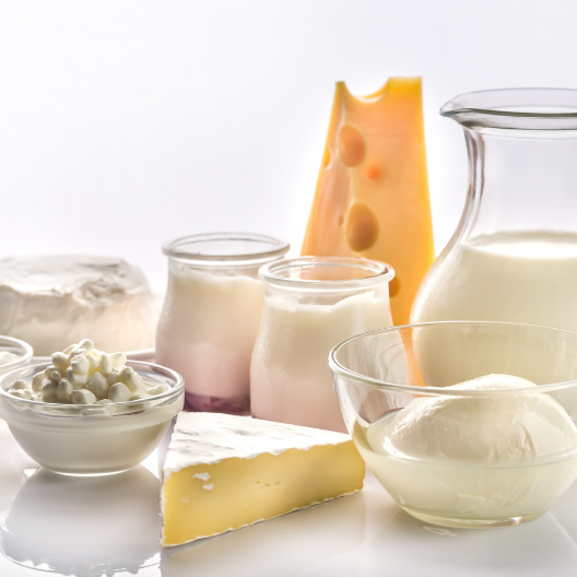 Variety of fresh dairy items including soft cheese, cottage cheese, yogurt jars, a wedge of Swiss cheese, milk in a glass jug, and mozzarella balls in a bowl, illustrating expert insights and exclusive market analysis for dairy commodity trends and Market Reports Subscriptions.